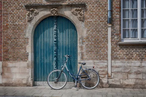 vélo stationné près d'une porte bleue d'une batisse