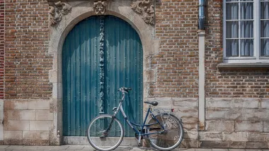 vélo stationné près d'une porte bleue d'une batisse